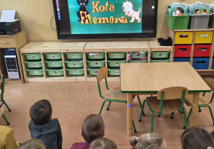 Dzieci oglądają bajkę o przygodach kota Filemona.
