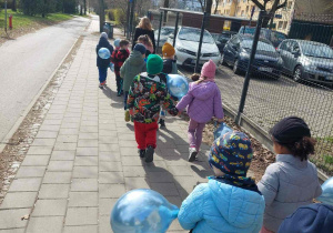 Dzieci spacerują z niebieskimi balonami na znak solidaryzmu z osobami z autyzmem.