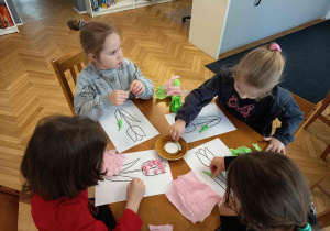 Dziewczynki wyklejają bibułą sylwetę tulipana.