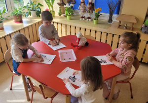 Dzieci ugniatają w rączkach kawałki plasteliny.