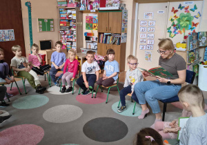 Dzieci słuchają opowiadania czytanego prze mamę Łukasza.