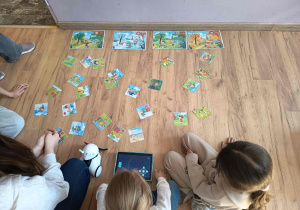 Dzieci bawia się robotem do programowania wraz z kartami tematycznymi i tabletem.