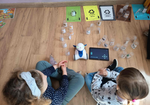 Dzieci obsługują robota edukacyjnego, używając tabletu do jego sterowania.