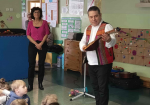 Muzyk prezentuje dzieciom instrument strunowy Charango.