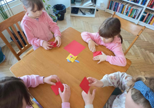 Dzieci zaangażowane w kreatywne zajęcia plastyczne przy stole.