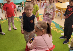 Chłopiec podchodzi do jubilatki złożyć jej życzenia.