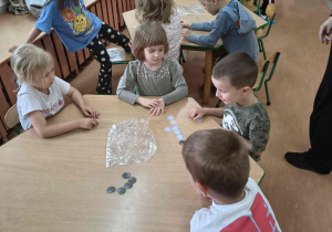 Dzieci przeliczają kartoniki z wizerunkiem monet.