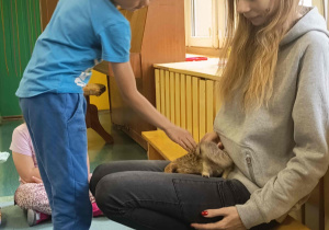 Chłopiec głaszcze surykatkę.