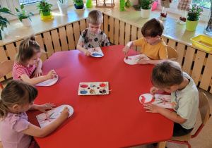 Dzieci wykonują pracę plastyczną z użyciem farb.