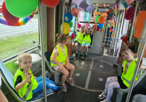 Dzieci jadą tramwajem ozdobionym balonami i kolorowymi dekoracjami z okazji Dnia Dziecka.