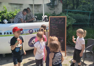 Dzieci przed mobilnym punktem sprzedaży lodów.