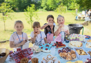 Dzieci jedzą przy stole piknikowym.