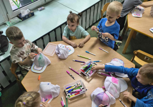Dzieci z grupy biedronek kreatywnie ozdabiają swoje nakrycie głowy.