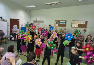 Przedszkolaki tańczą taniec z kwiatami.