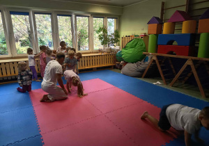 Instruktor asekuruje dziewczynkę wykonującą przewrót.
