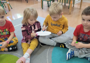 Dzieci przekazują sobie papierowy talerz za pomocą klamerki.
