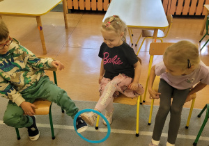 Dziewczynka przekazuje chłopcu kolorową obręcz.