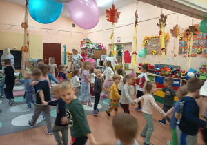 Dzieci trzymając się za ręce, tańczą w kółku.