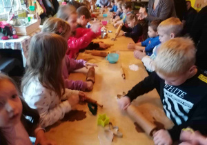Dzieci wałkują ciasto na pierniki.