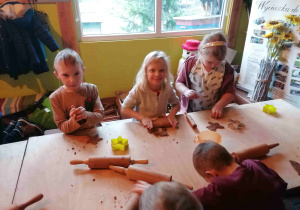 Dzieci wyciskają foremkami kształty pierników.