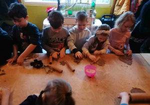 Dzieci wyciskają foremkami kształty pierników.