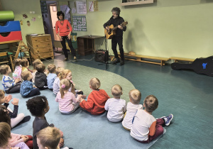 Dzieci słuchają gry na gitarze.