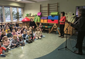 Dzieci słuchają gry na instrumencie.