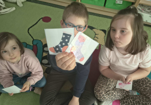 Chłopiec pokazuje obrazki z kolorowymi skarpetkami.