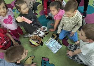 Dziewczynka trzyma kopertę z obrazkami wielkanocnymi w środku.