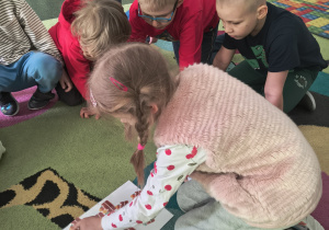 Dziewczynka rozwiązuje działanie matematyczne z wykorzystaniem ilustracji przedstawiających kawałki babki wielkanocnej.