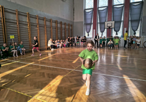 Dziewczynka biegnie do półmetka z piłką lekarską.
