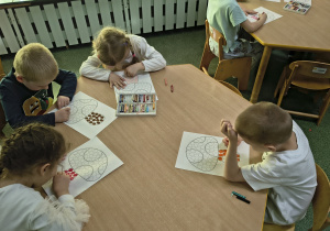 Dzieci malują pastelami kropki na grzybie.
